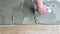 A tiler applies adhesive to the floor to install ceramic tiles. Laying tiles at a construction site. Selective focus, plenty of