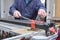 Tiler hands cutting a ceramic wood effect tile with a manual tile cutter.