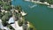 tilt aerial footage of the green waters of Lake Gregory with a jungle gym on the water, boats, homes along the hillside, cars