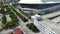 tilt aerial footage of LoanDepot Park surrounded by lush green palm trees, grass and plants, cars on the street, buildings