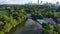 tilt aerial footage at Piedmont Park with tennis courts, a pool, Lake Clara Meer, lush green trees and grass, skyscrapers