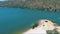 tilt aerial footage of the rippling blue waters of Silverwood Lake with a beach and people swimming in the water