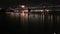 tilt aerial footage of the San Francisco Oakland Bay Bridge with lights and ships sailing in the bay at night in San Francisco