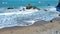 tilt aerial footage of the waves rolling into the shore at Mile Rock Beach with large rocks and silky brown sand