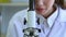 Tilt-down video shot of Female medical research scientists adding pipette dropping a colored liquid to petri dish to conduct scie