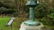 tilt footage of a bronze Japanese lantern in the Japanese Tea Garden at Golden Gate Park with lush green trees, plants, grass