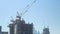 Tilt up panorama of huge construction cranes are in unfinished building in big modern city