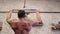 Tilt up of shirtless sportsman doing pull-ups on bars during cross-training workout at gym