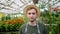 Tilt-up shot of man in apron farmer carrying wooden box of organic vegetables