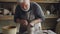 Tilt-up shot of skilled craftsman professional potter molding clay and making pot on throwing wheel. Grey haired bearded