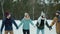 Tilt-up slow motion of happy young friends skating on frozen lake holding hands laughing