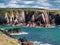 Tilted strata of red sandstone sedimentary bedrock cliffs in Pembrokeshire, Wales, UK