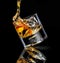 Tilted stylish glass of whiskey. Pouring over cubes ice on black background with reflection