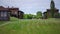 Tilting shot of green meadow at eco-resort outdoors in slow motion. Wide shot beautiful landscape with wooden villas on