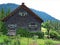 Timber cottage with cultivated yard in green landscape