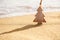 Timber wooden Christmas tree on a sand on the tropical beach near ocean, summer Christmas and winter holyday concept