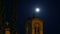 Time-lapse of church building at night against moon movement in sky
