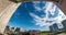 Time lapse clip of white fluffy rolling clouds view of the city from the balcony of the house. Wide fish eye angle