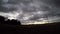 Time lapse of clouds passing over wind towers at sunset.