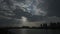 Time-lapse, dark clouds floating over city and lake, sunlight through thick clouds, light beam