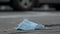 Time-lapse, discarded medical face mask lies on the sidewalk, on the background walks birds, peoples and cars drive. Face masks po