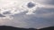 Time lapse of dusk light and white clouds shining bright while rolling over the mountains and thick vegetation shot in Tasmania,