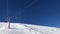 Time lapse hyper lapse video clip of four person ski chair lift in blue sky going up a mountain with skiers on the piste below