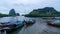 Time-lapse longtail fishing boats in the pier white storm clouds flowing fast over mountain rainforest, mangrove trees in the sea