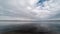 Time lapse of low-flying white and fluffy clouds over the calm water surface
