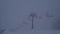 Time Lapse - a moving chairlift, skiers,fog and falling snow in ski area in winter.