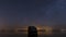 Time lapse of the night sky with the ocean and a huge boulder