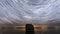 Time lapse of the night sky with star trails and the ocean with a huge boulder