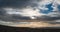 Time lapse on pebble beach at dusk with sun obscured behind flat low clouds