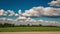 Time lapse of sky background with tiny fluffy clouds in sunny day over forest with gravel road