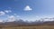 Time-lapse of sun movement on crystal clear sky with clouds over snow mountain top. Yellow grass at autumn high altitude
