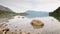 Time Lapse video of stone in water of mountain lake. Gentle waves on autumn lake, forest islands and mountains in background.