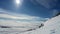 Time lapse video video on tourists driving snowmobiles and camping at side of mountain. Moving camera view over sky, clouds, snow