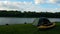 Time Lapse view of the tent and yellow kayak on the shore river. Small clouds on the horizon.