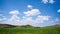 Time-lapse of white clouds moving in blue sky over grassland