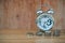 Time is Money Concept : Alarm clock put on wooden table with stack of silver money coins Baht in foreground.