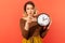 Time to act. Serious woman holding big wall clock pointing finger at you, motivation, warning about deadline