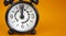 Time to fasting symbol. Beautiful black alarm clock with words `eating fasting`. Beautiful orange background. Copy space. Health