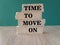 Time to move on - concept words on brick blocks on wooden table. Green background.