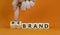 Time to rebrand symbol. Businessman turns wooden cubes and changes the word `brand` to `rebrand`. Beautiful orange background.