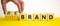 Time to rebrand symbol. Businessman turns wooden cubes and changes the word `brand` to `rebrand`. Beautiful yellow table, whit
