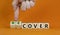 Time to recover symbol. Businessman turns wooden cubes and changes the word `cover` to `recover`. Beautiful orange background.