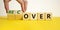 Time to recover symbol. Businessman turns wooden cubes and changes the word `over` to `recover`. Beautiful yellow table, white