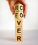 Time to recover symbol. The word `recover` on wooden cubes. Male hand. Beautiful white background, copy space. Business and