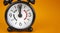 Time to renew symbol. Beautiful black alarm clock with words `time to renew`. Beautiful orange background. Copy space. Business