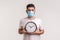 Time to stop coronavirus. Man in protective hygienic mask holding clock, warning of novel virus epidemic